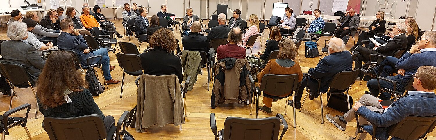 Es werden Sesselkreise gezeigt mit einer Diskussionsrunde von 5 Personen in der Mitte.