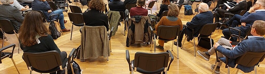 Es werden Sesselkreise gezeigt mit einer Diskussionsrunde von 5 Personen in der Mitte.